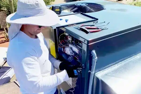 HVAC technician performing maintenance on air conditioning unit, showcasing essential service for Arizona's extreme summer heat.