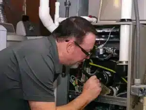 HVAC technician inspecting a furnace for maintenance and repair in a residential setting, emphasizing Worlock Air's heating services in Sun City, AZ.