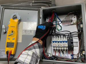 HVAC technician using a multimeter to inspect electrical connections inside a heating system control panel, emphasizing professional maintenance and repair services for residential heating in Peoria, AZ.