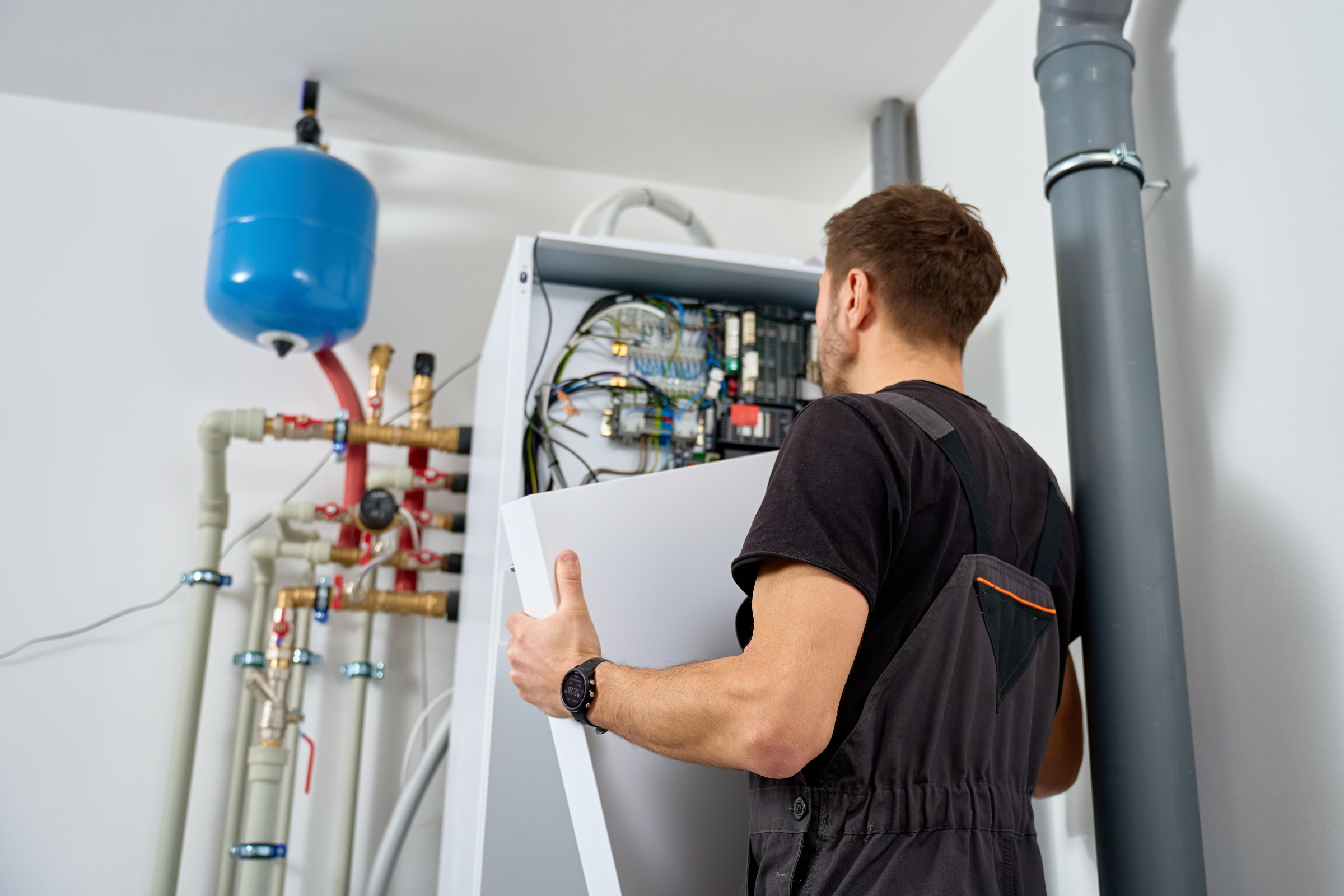 Repair vs Replacement What to Consider Technician servicing a heating system, handling equipment and inspecting components in a residential setting, emphasizing HVAC repair and maintenance.